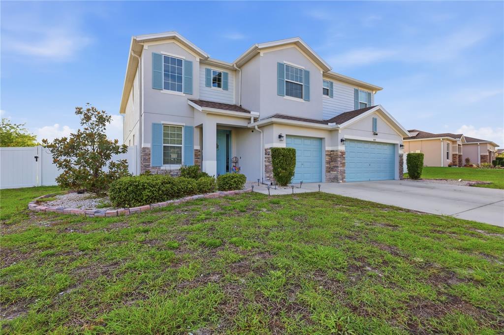 A two-story suburban house features light-colored stucco, blue shutters, a two-car garage, and landscaping — 1419 AVILA AVENUE, DELTONA, FL