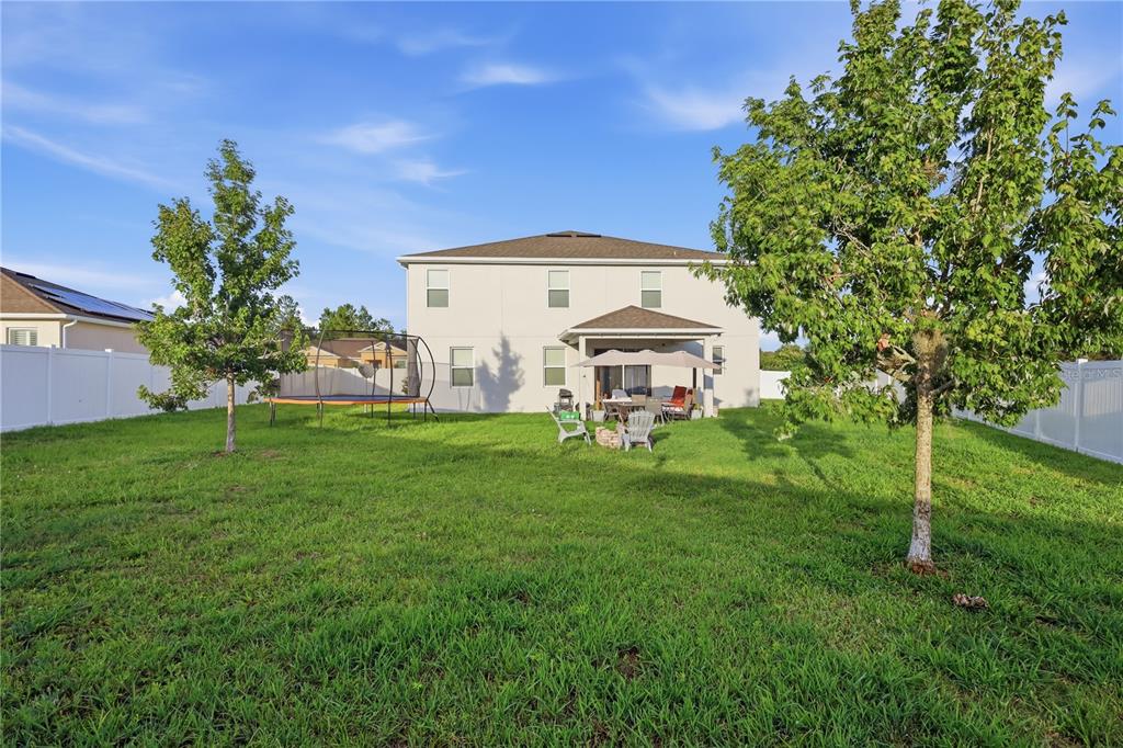A two-story house with a backyard, patio, trampoline, and two trees on a sunny day — 1419 AVILA AVENUE, DELTONA, FL