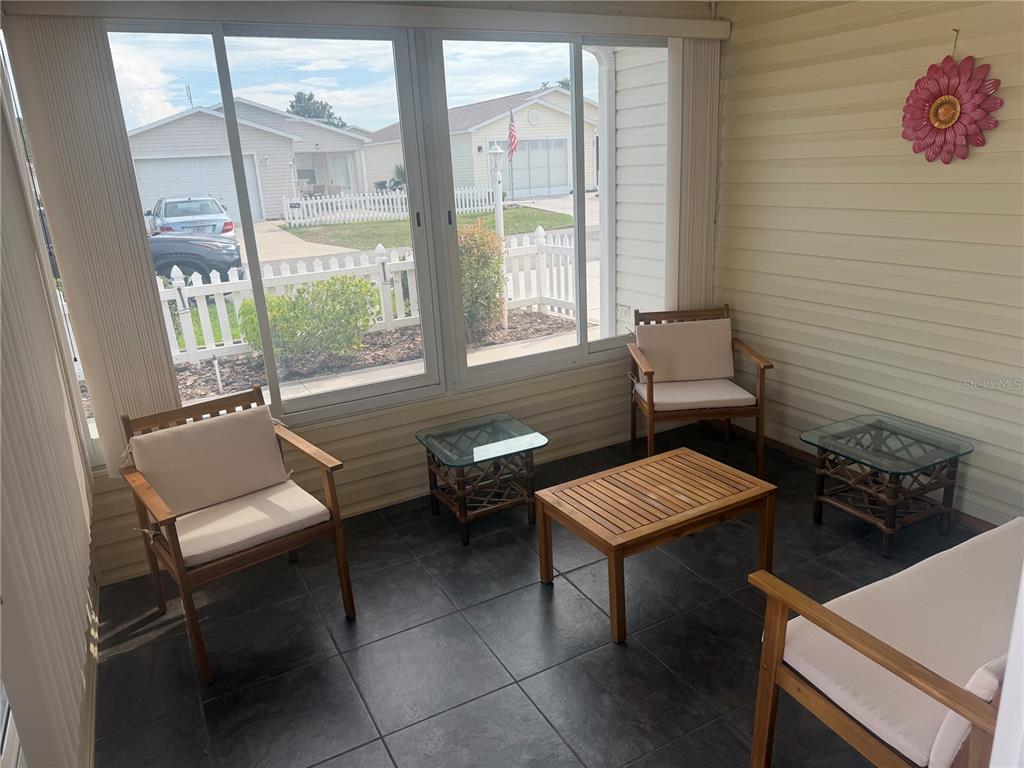 A sunroom features tile flooring, three wooden chairs with cushions, and two glass-topped side tables — 484 HILDALGO DRIVE, LADY LAKE, FL