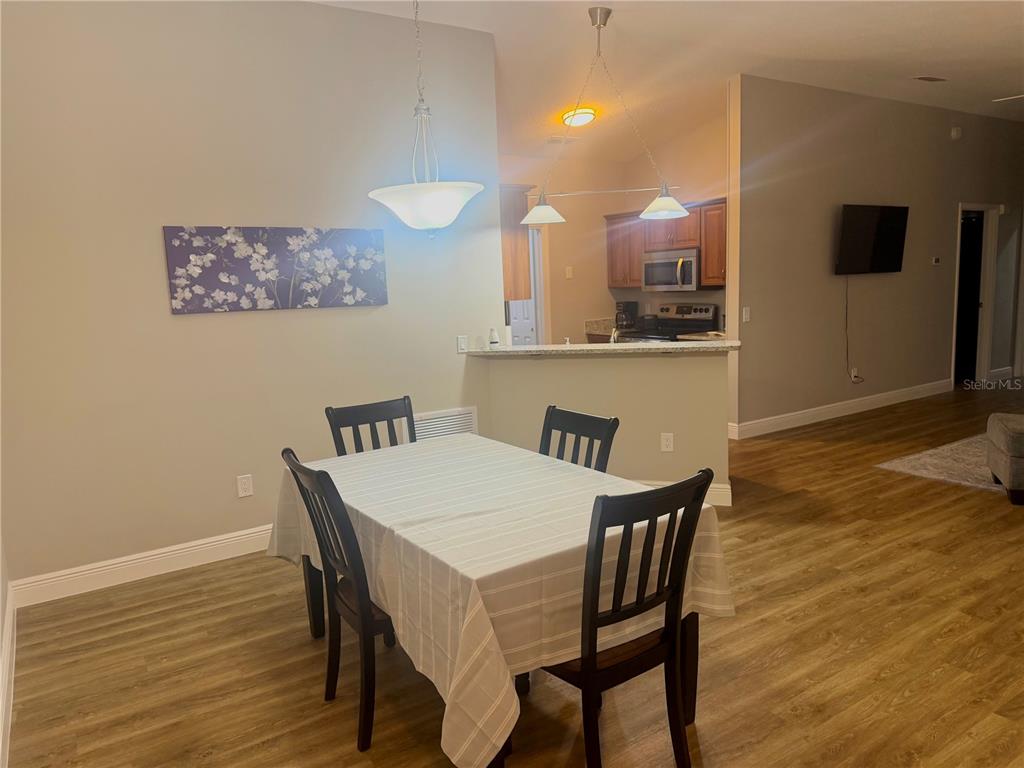 A dining area with a table and chairs sits in front of an open kitchen — 484 HILDALGO DRIVE, LADY LAKE, FL