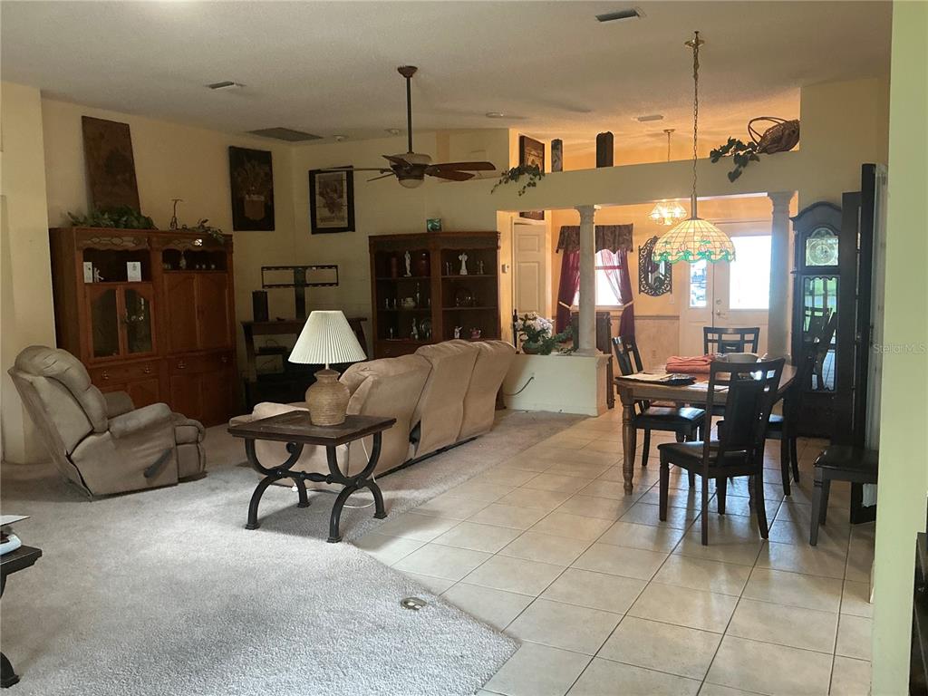 A living room features a beige sofa, a coffee table, and a fireplace with shelving — 867 CORTEZ AVENUE, THE VILLAGES, FL