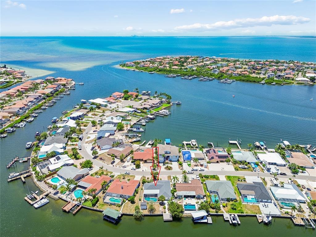 An aerial view shows a waterfront residential neighborhood with a red arrow pointing toward a house — 6331 COCOA LANE, APOLLO BEACH, FL