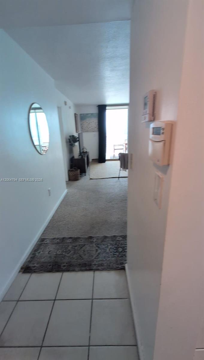 A hallway with tiled flooring leads into a carpeted living area with a balcony door — 1200 S Brickell Bay Dr # 3317, Miami FL 33131, MIAMI, FL