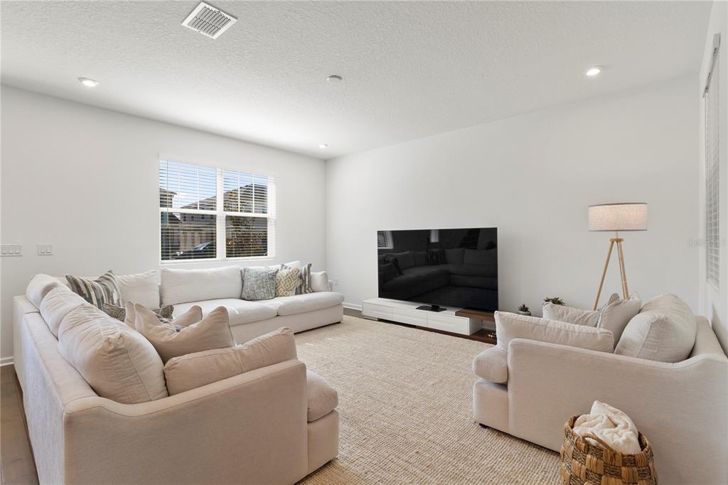 A living room features a large sectional sofa, a television on a console, and a rug — 11356 SUNSAIL AVENUE, ORLANDO, FL