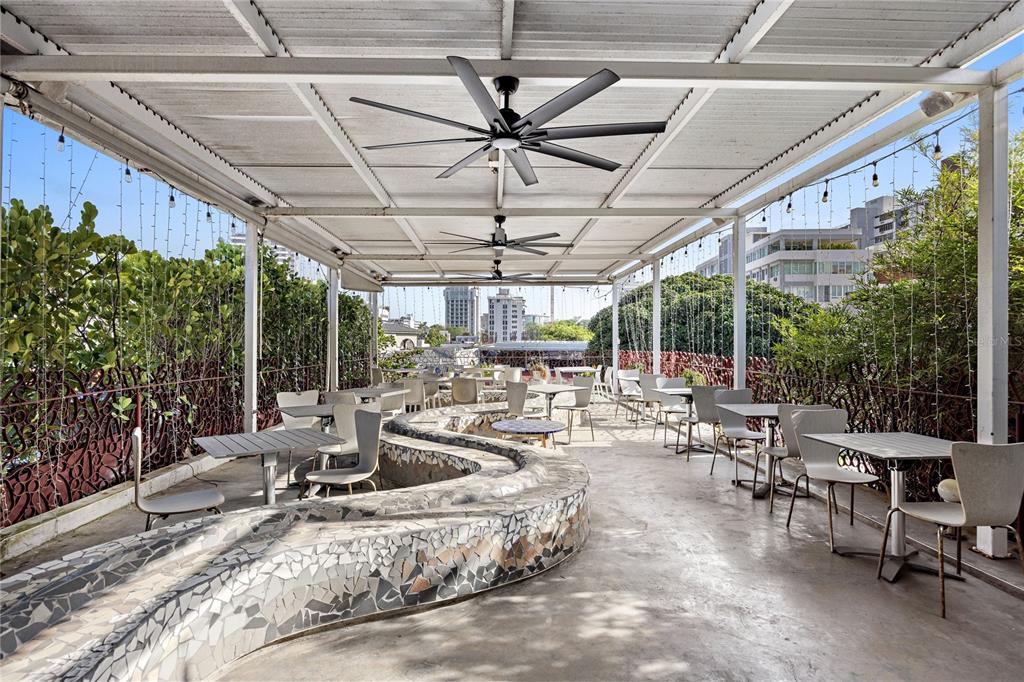 An outdoor covered patio features a winding mosaic bench, dining tables, and large ceiling fans — 1105 MAGDALENA AVENUE UNIT Condal, SAN JUAN, PR