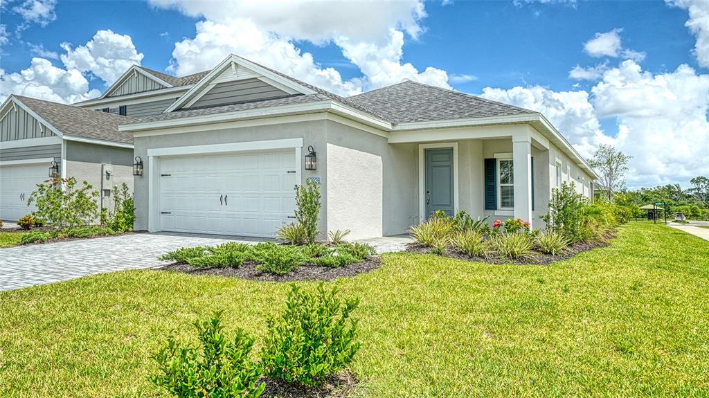 A single-story suburban house with a gray stucco exterior, a two-car garage, and green lawn — 10026 CROSS RIVER TRAIL, PARRISH, FL
