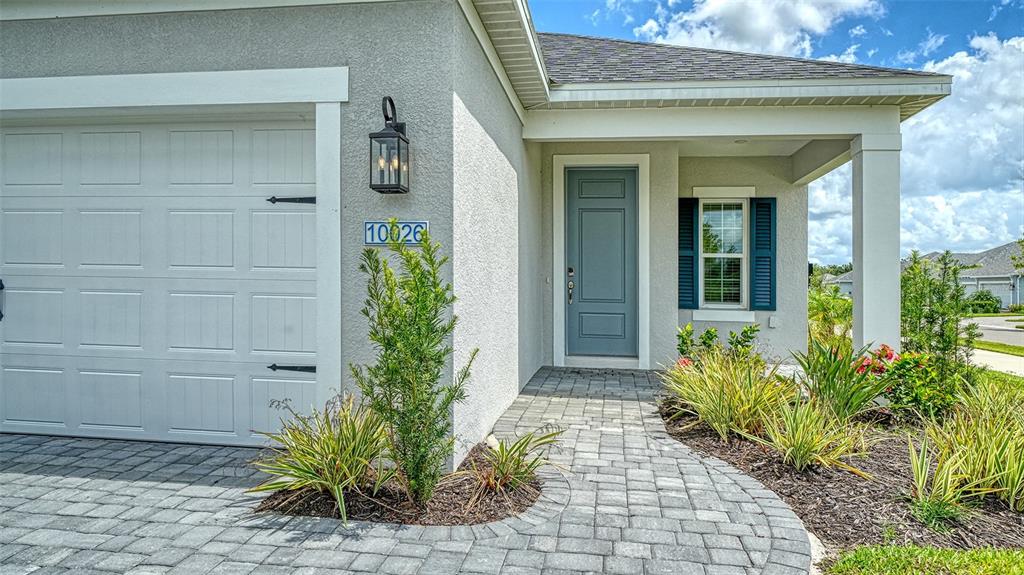 The exterior of a house features a gray garage door, blue front door, and pavers — 10026 CROSS RIVER TRAIL, PARRISH, FL