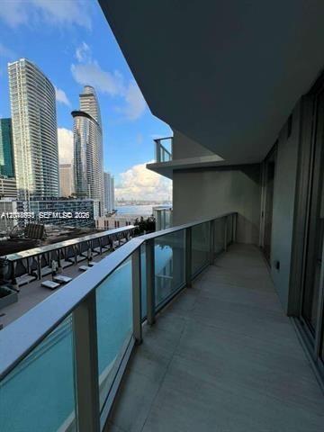A balcony with a glass railing overlooks a swimming pool and city skyscrapers — 77 SE 5th St # 1605, Miami FL 33131, MIAMI, FL