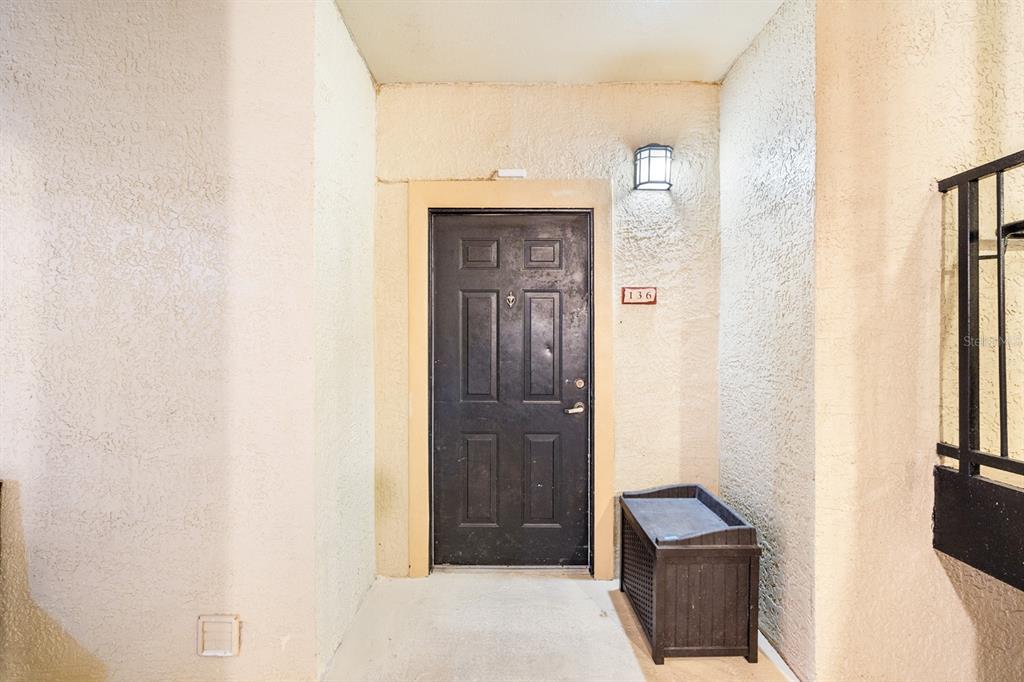 A dark brown front door with the number 136 is set in a textured beige alcove — 132 VISTA VERDI CIRCLE UNIT 136, LAKE MARY, FL