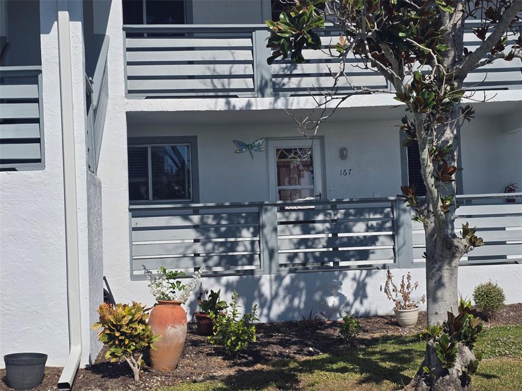 The exterior of a ground-floor apartment unit features a private patio with gray horizontal railings — 6800 PLACIDA ROAD UNIT 167, ENGLEWOOD, FL