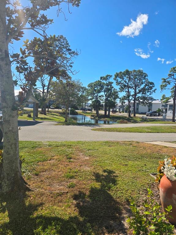 A view of a grassy yard, a small pond, and residential buildings under a blue sky — 6800 PLACIDA ROAD UNIT 167, ENGLEWOOD, FL