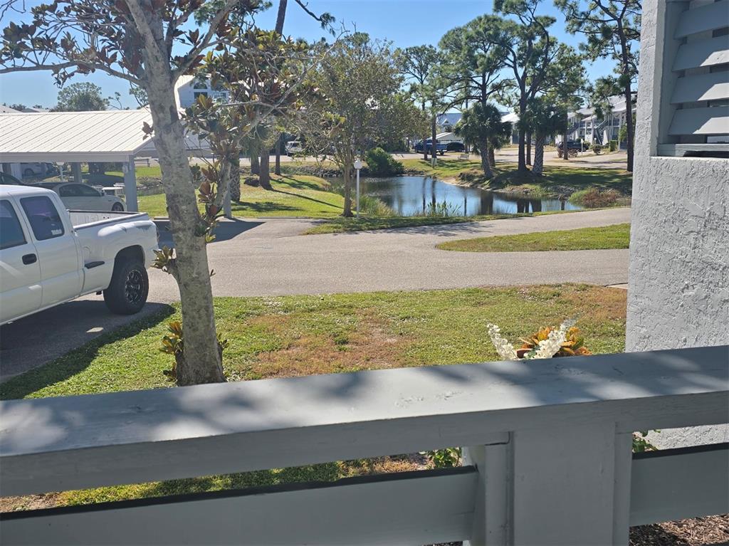 A view from a porch overlooking a grassy yard, a small pond, and parked vehicles — 6800 PLACIDA ROAD UNIT 167, ENGLEWOOD, FL