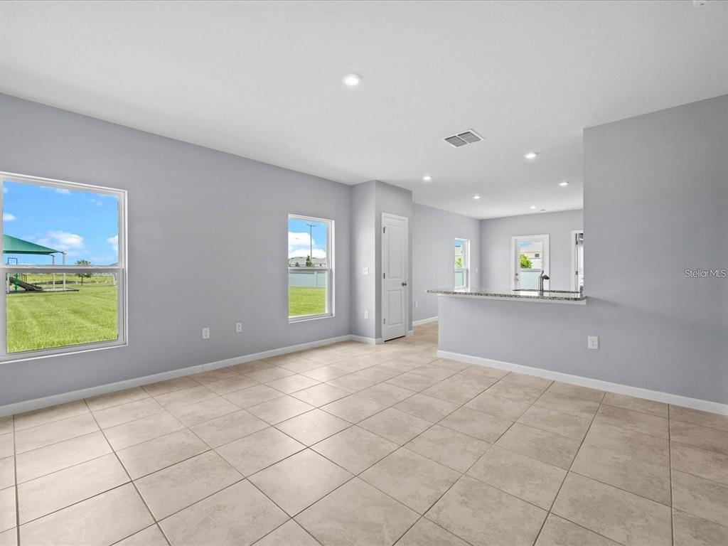 An open-concept living area with light gray walls, tile flooring, and a kitchen breakfast bar — 1403 MADISON CIRCLE, HAINES CITY, FL