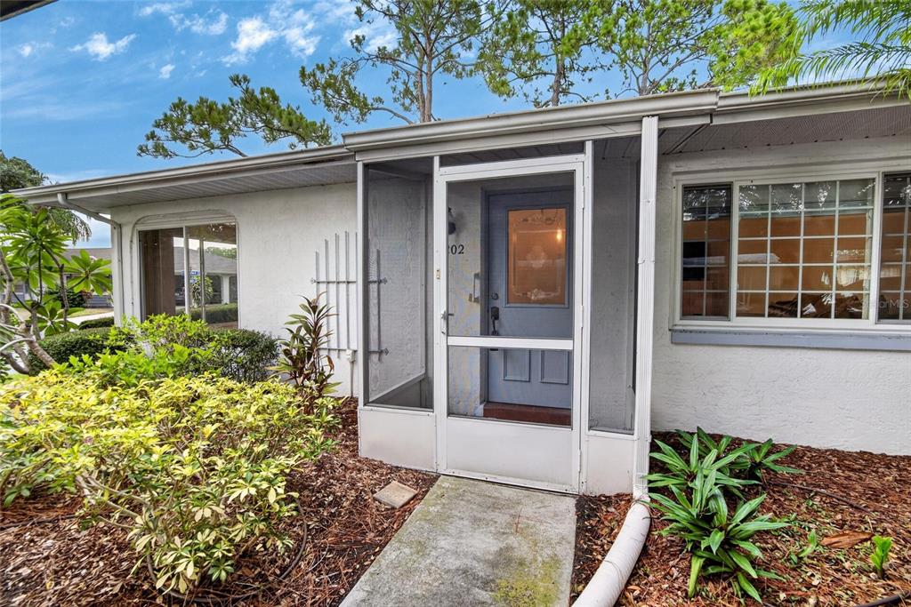 The exterior of a white house features a screened-in front porch and a blue door — 2202 HORSHAM PLACE, SUN CITY CENTER, FL