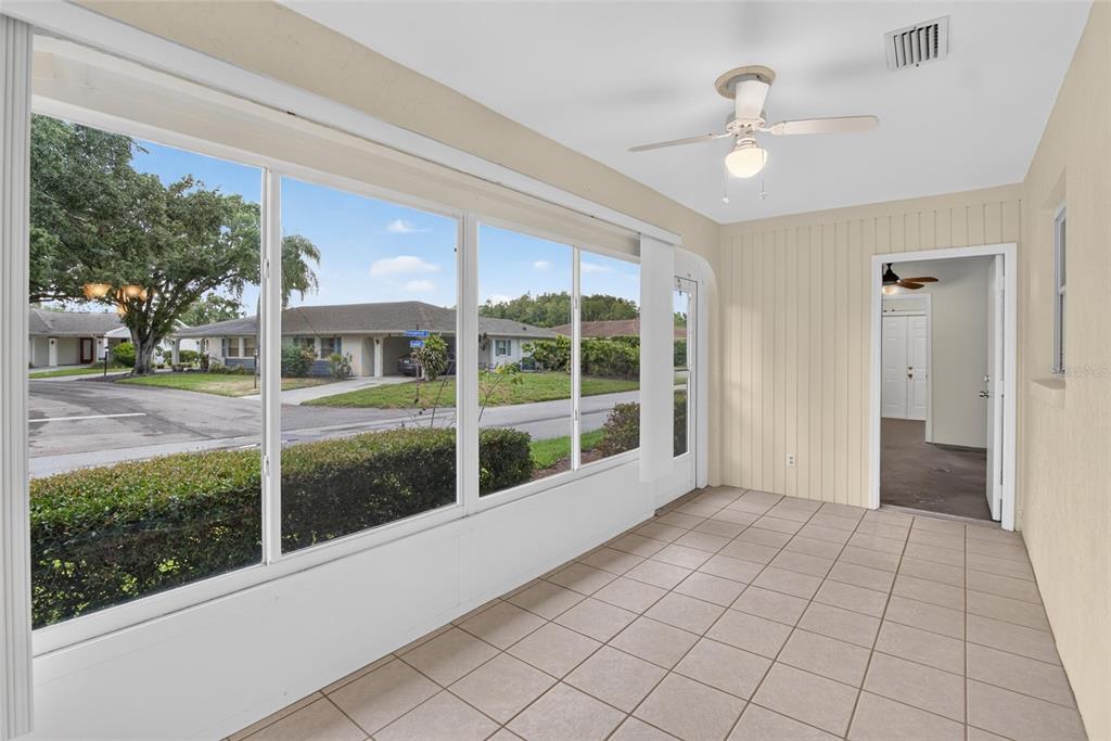 A tiled sunroom features large windows overlooking a street and a ceiling fan — 2202 HORSHAM PLACE, SUN CITY CENTER, FL