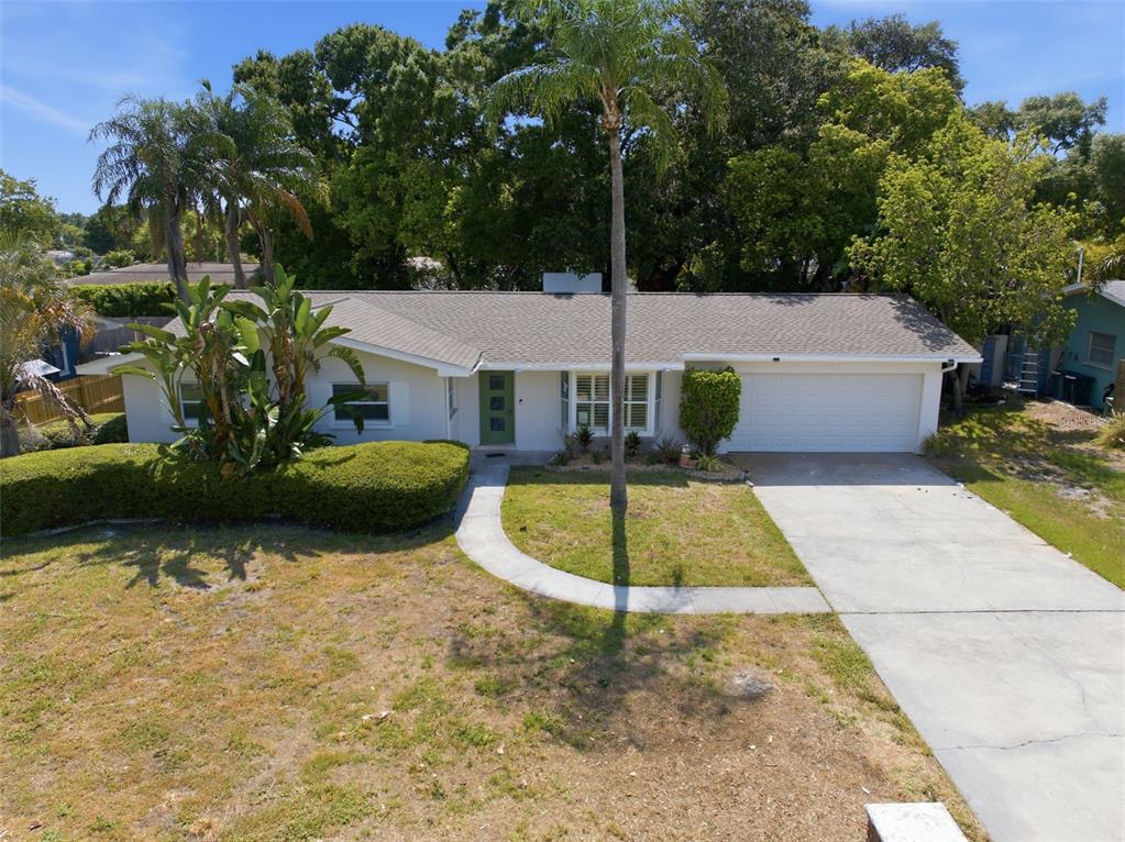 A single-story house with a white exterior, a green front door, and a concrete driveway — 1360 IRVING AVENUE, CLEARWATER, FL
