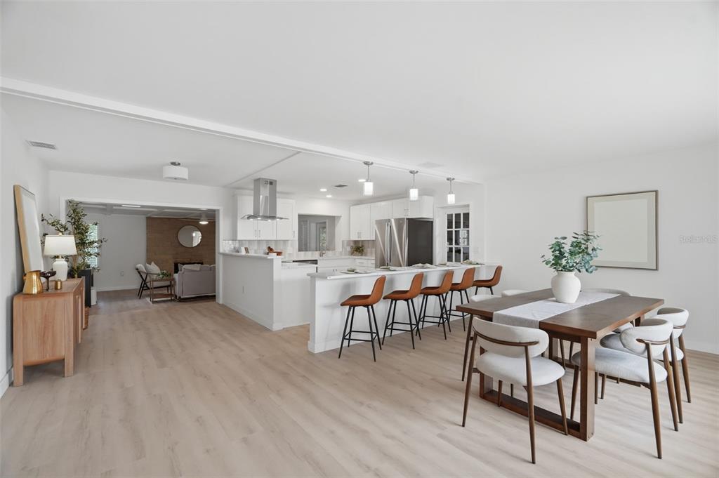An open-concept kitchen and dining area features white cabinetry, a breakfast bar, and wood flooring — 1360 IRVING AVENUE, CLEARWATER, FL
