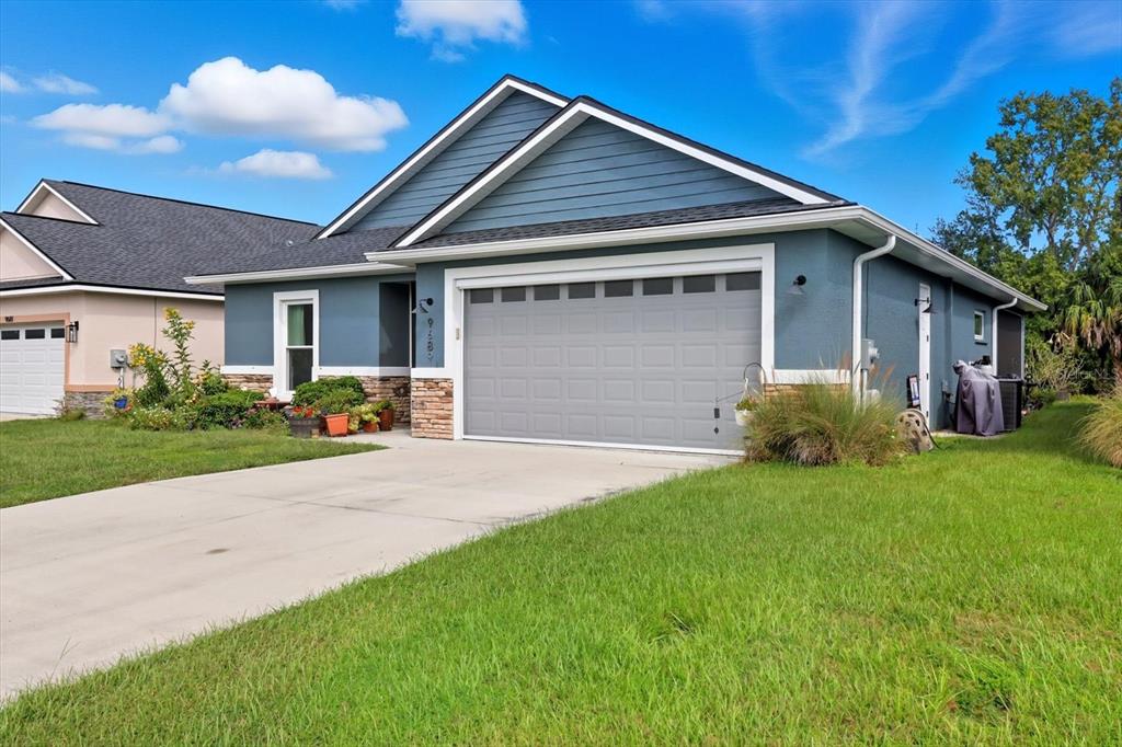 A blue single-story house with a two-car garage, stone accents, and a concrete driveway — 9689 E WHITE EGRET PATH, INVERNESS, FL