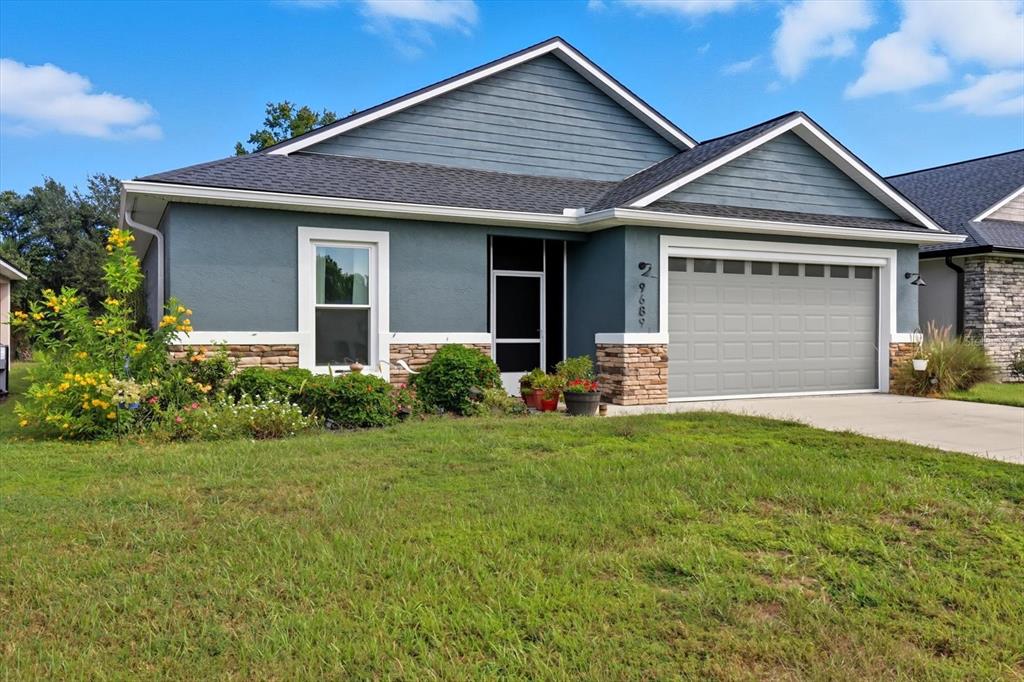 A single-story house with blue siding, a stone facade, and a two-car garage — 9689 E WHITE EGRET PATH, INVERNESS, FL