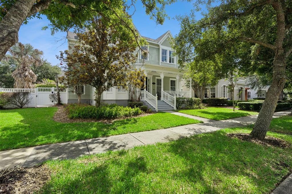 A two-story light green house with a front porch sits behind a grassy lawn — 928 JASMINE STREET, CELEBRATION, FL