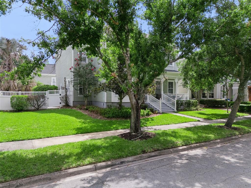 A two-story light green house with a front porch and white picket fence — 928 JASMINE STREET, CELEBRATION, FL