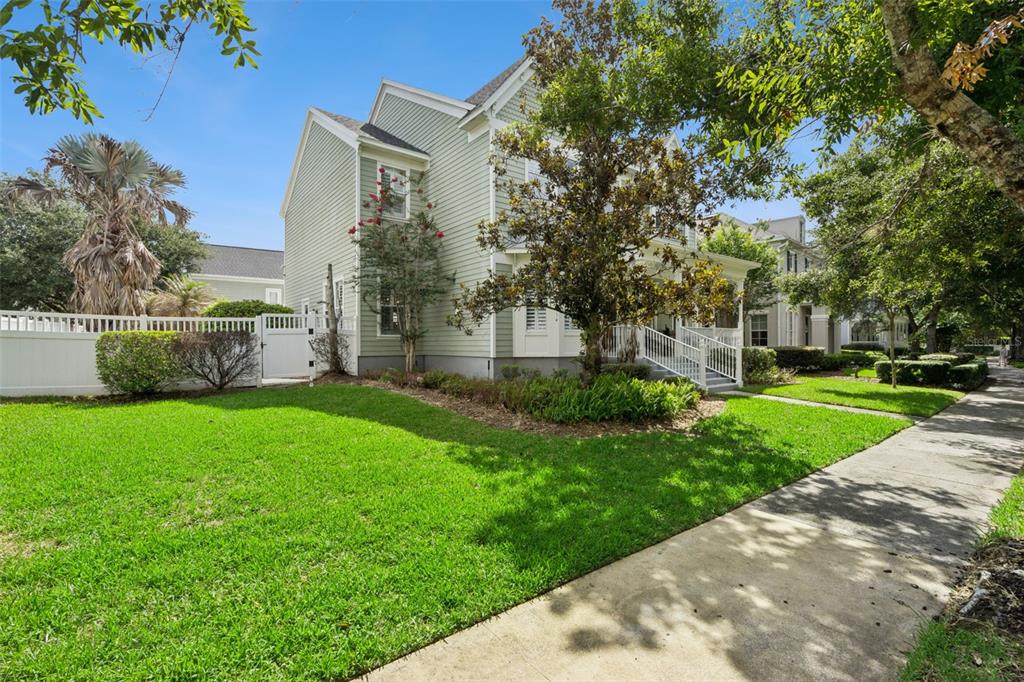 A light green two-story house with a white fence and a sidewalk in the foreground — 928 JASMINE STREET, CELEBRATION, FL