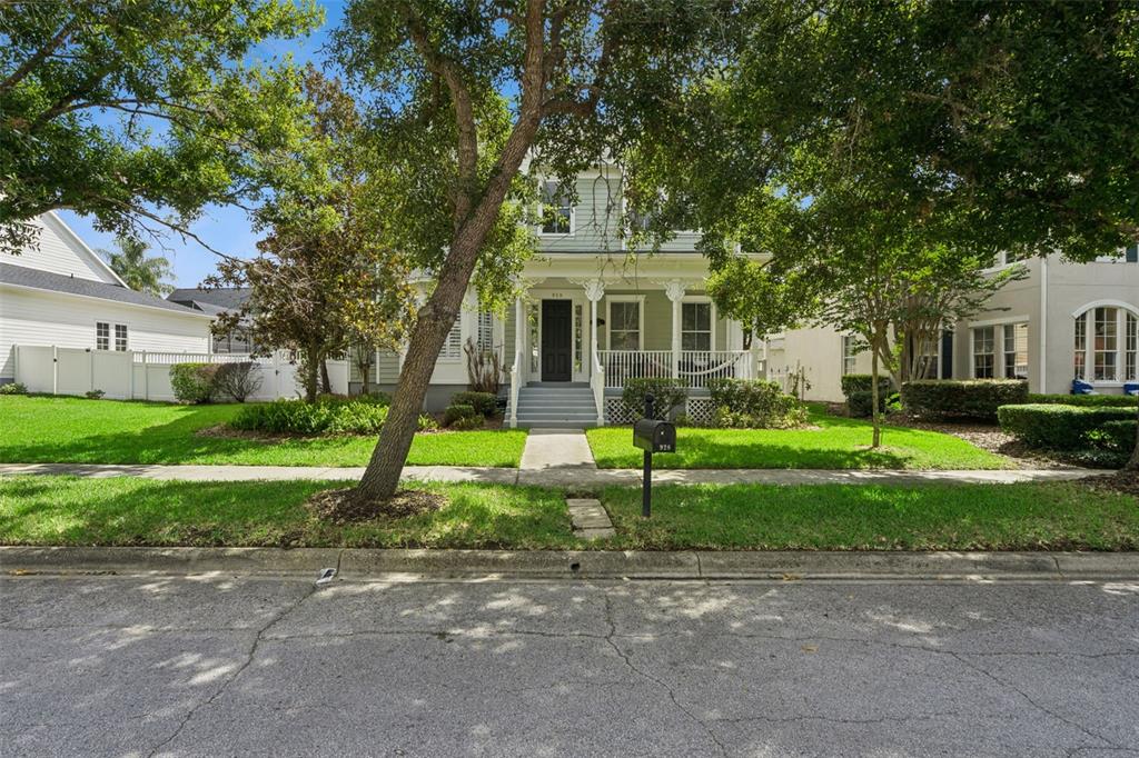 A two-story light green house with a front porch sits behind a grassy lawn — 928 JASMINE STREET, CELEBRATION, FL