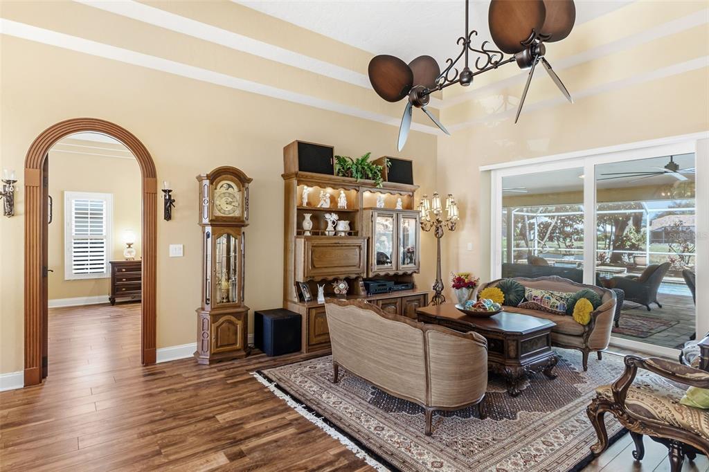 A living room features wood-look flooring, an arched doorway, a ceiling fan, and sliding glass doors — 8309 SHADOW PINE WAY, SARASOTA, FL