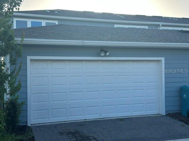 A white garage door is set into the blue-sided exterior of a residential building — 14322 SAPELO BEACH DRIVE, ORLANDO, FL