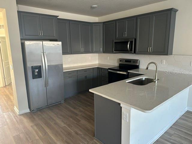A kitchen features dark gray cabinets, stainless steel appliances, and a light-colored quartz countertop — 14322 SAPELO BEACH DRIVE, ORLANDO, FL