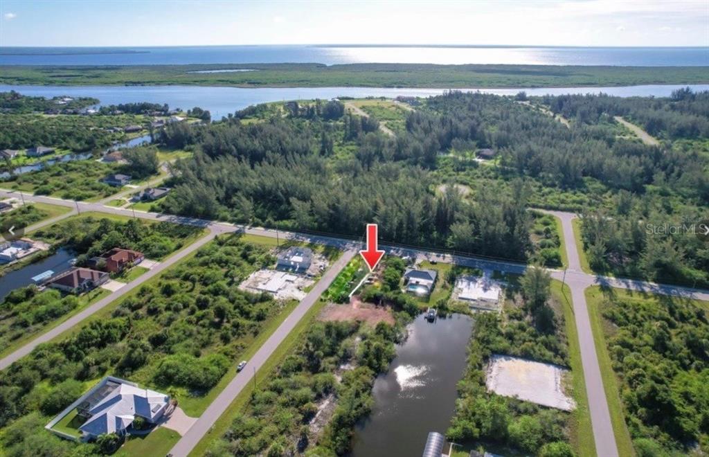 An aerial view shows a vacant lot marked by a red arrow near a pond — 15802 APPLEWHITE CIRCLE, PORT CHARLOTTE, FL