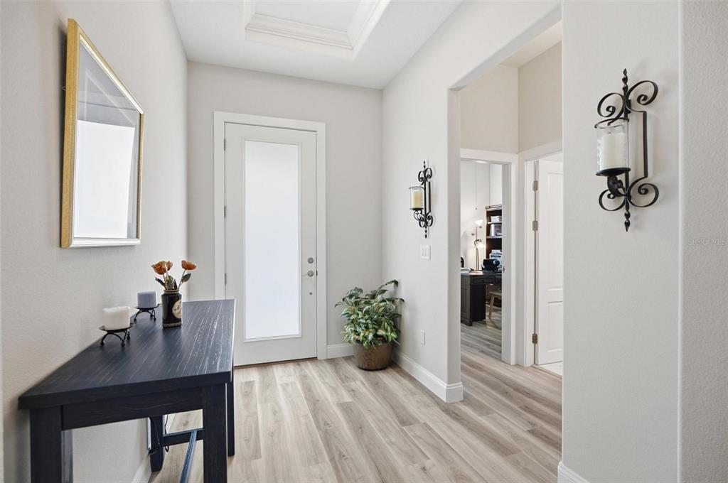 A bright entryway features light wood-look flooring, a dark console table, and a frosted glass door — 17 GREEN CIRCLE, PALM COAST, FL