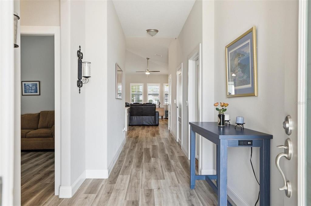 A bright entryway with wood-look flooring leads into a living area with a ceiling fan — 17 GREEN CIRCLE, PALM COAST, FL