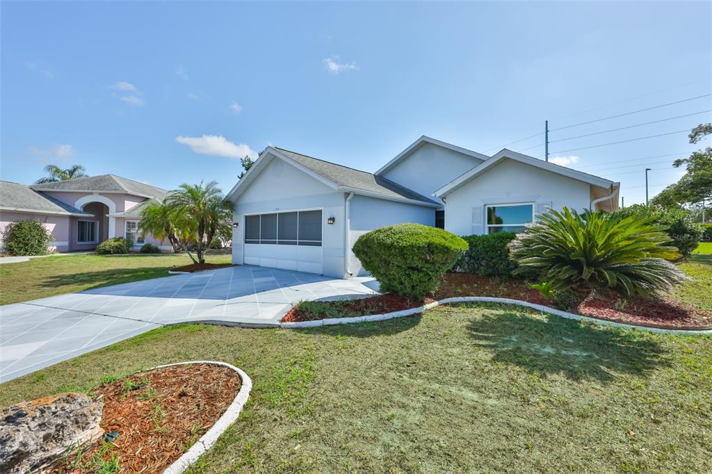 A light-colored single-story house with a two-car garage and a paved driveway — 235 LINGER LANE, SUN CITY CENTER, FL