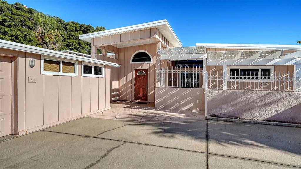 The exterior of a light-colored house features a wooden front door and a concrete driveway — 355 S SHORE DRIVE, SARASOTA, FL