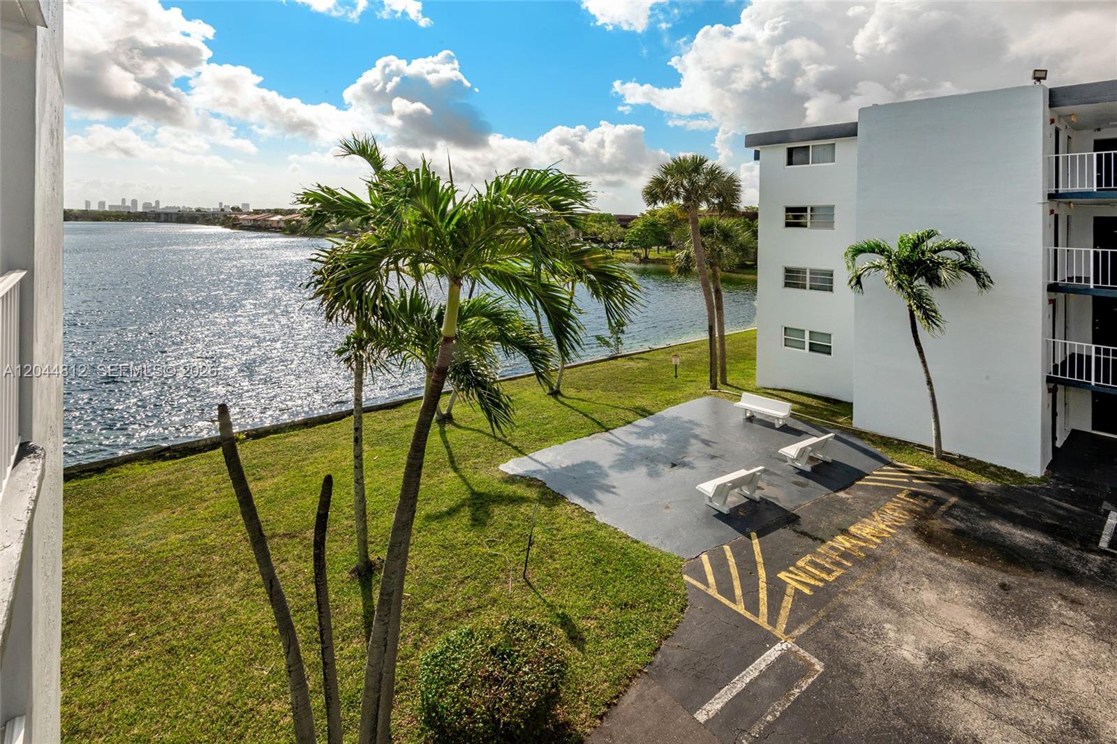 An elevated view shows a grassy area with palm trees, benches, and a lake — 447 NE 195th St # 214, Miami FL 33179, MIAMI, FL