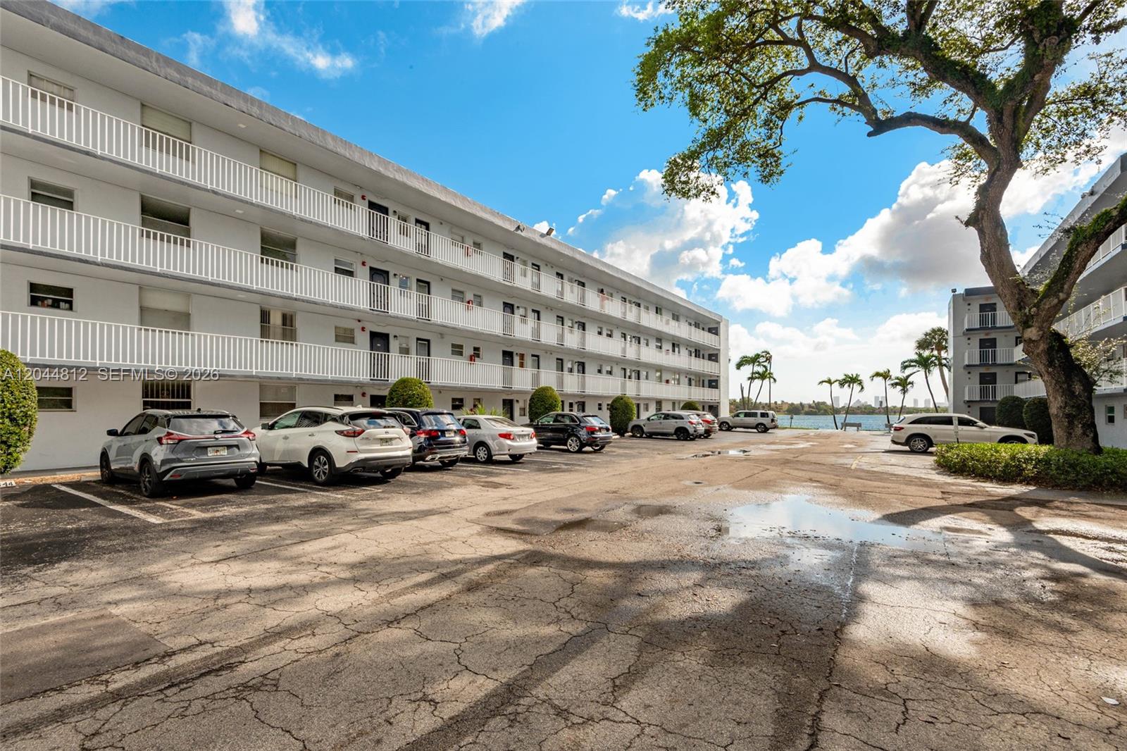 A multi-story apartment building with a parking lot and a view of the water — 447 NE 195th St # 214, Miami FL 33179, MIAMI, FL