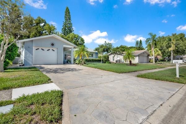 A single-story house with a gray exterior, a paved driveway, and palm trees in the yard — 133 STAFFORD CIRCLE, PALM HARBOR, FL
