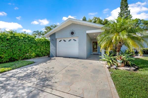 A single-story house with a light gray exterior, a white garage door, and a stone driveway — 133 STAFFORD CIRCLE, PALM HARBOR, FL