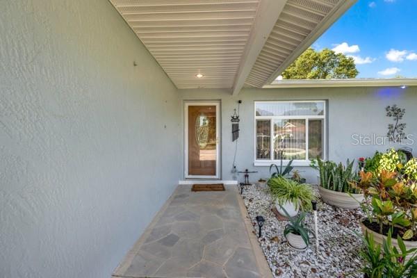 A stone walkway leads to the front door of a house with a covered porch — 133 STAFFORD CIRCLE, PALM HARBOR, FL