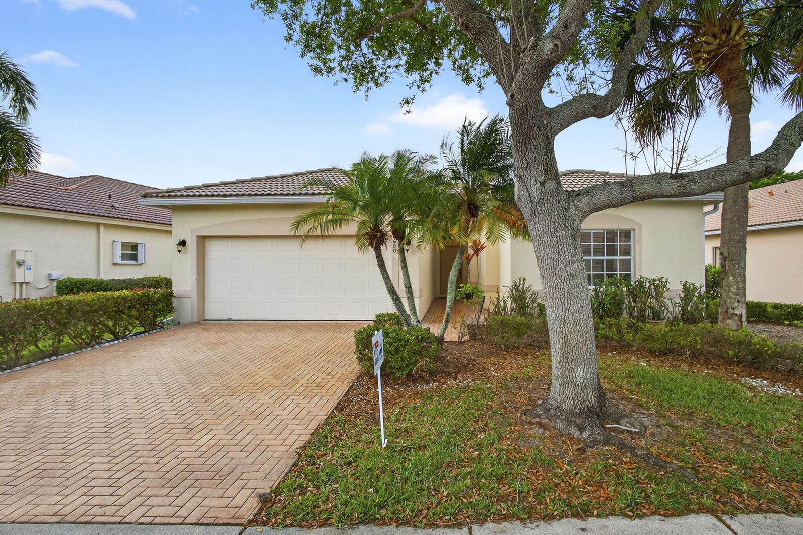 A single-story house with a brick paver driveway, a two-car garage, and mature landscaping — 8600 Pine Cay, West Palm Beach FL 33411, WEST PALM BEACH, FL