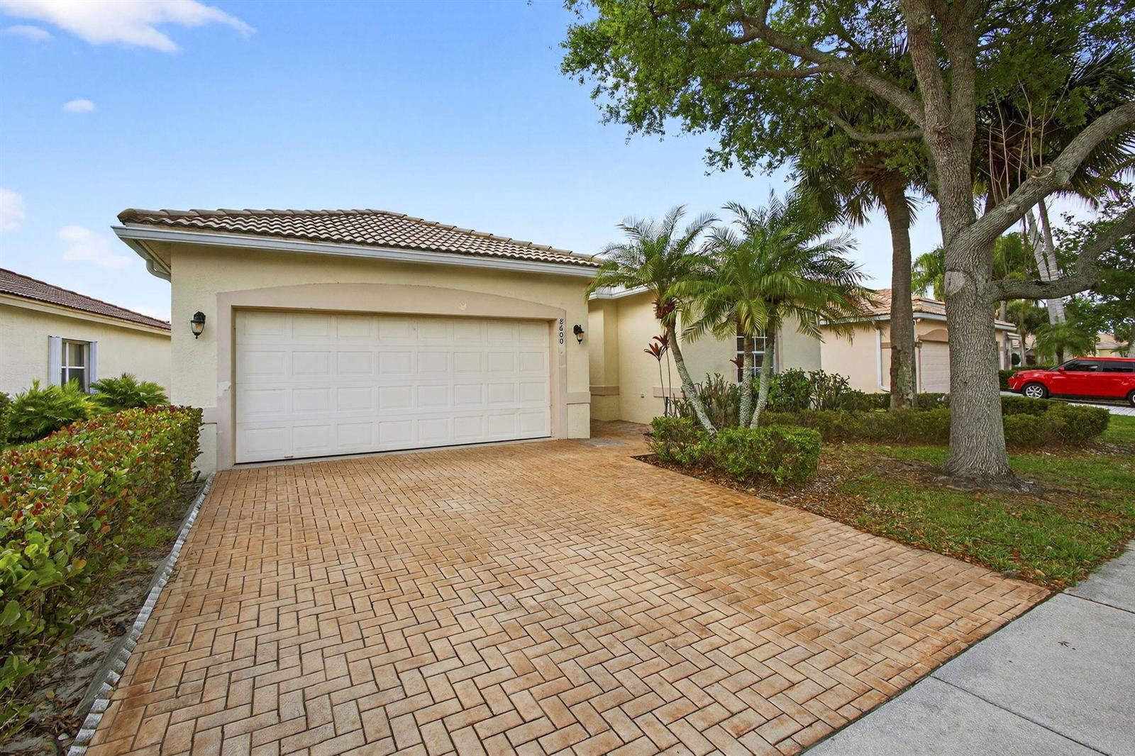 A single-story house with a paved driveway, a two-car garage, and palm trees — 8600 Pine Cay, West Palm Beach FL 33411, WEST PALM BEACH, FL