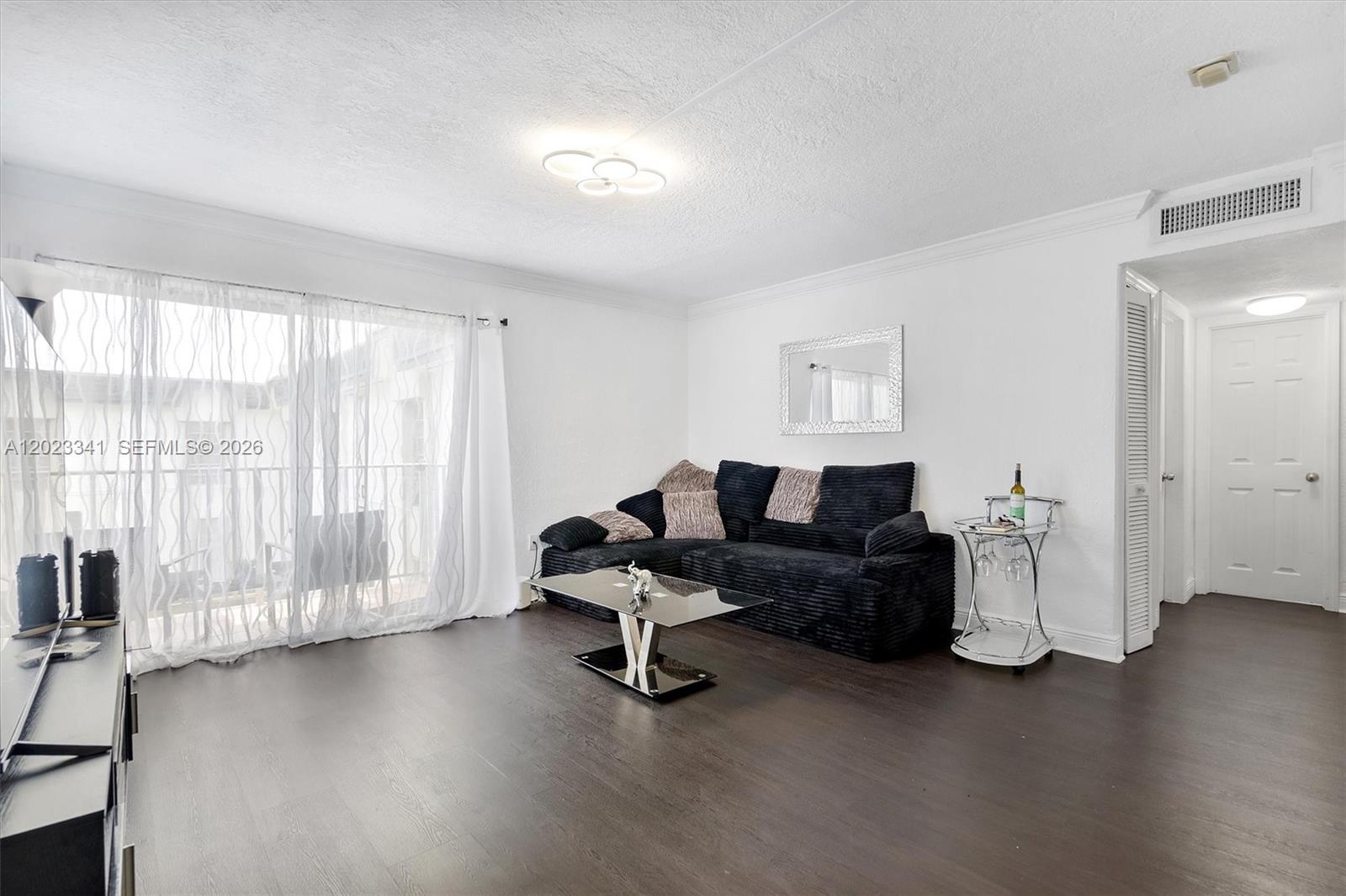A living room features dark wood flooring, a black sectional sofa, and a glass coffee table — 7232 SW 94th Pl # E6, Miami FL 33173, MIAMI, FL