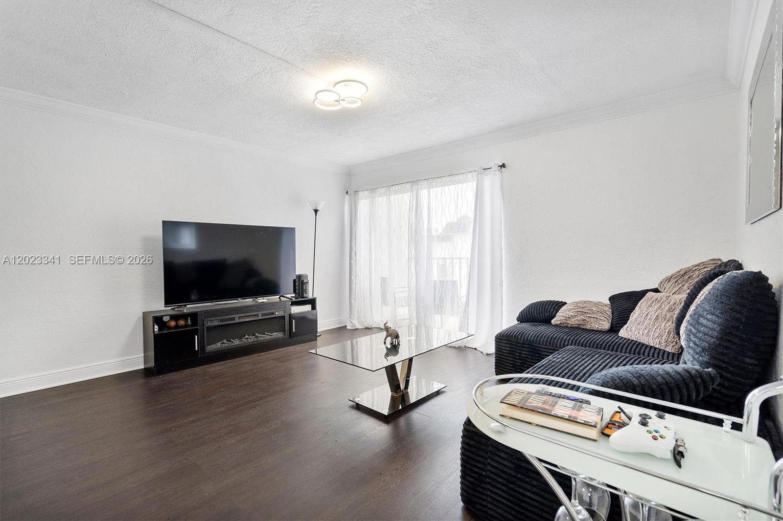 A living room features dark wood floors, a black sectional sofa, and a television console — 7232 SW 94th Pl # E6, Miami FL 33173, MIAMI, FL
