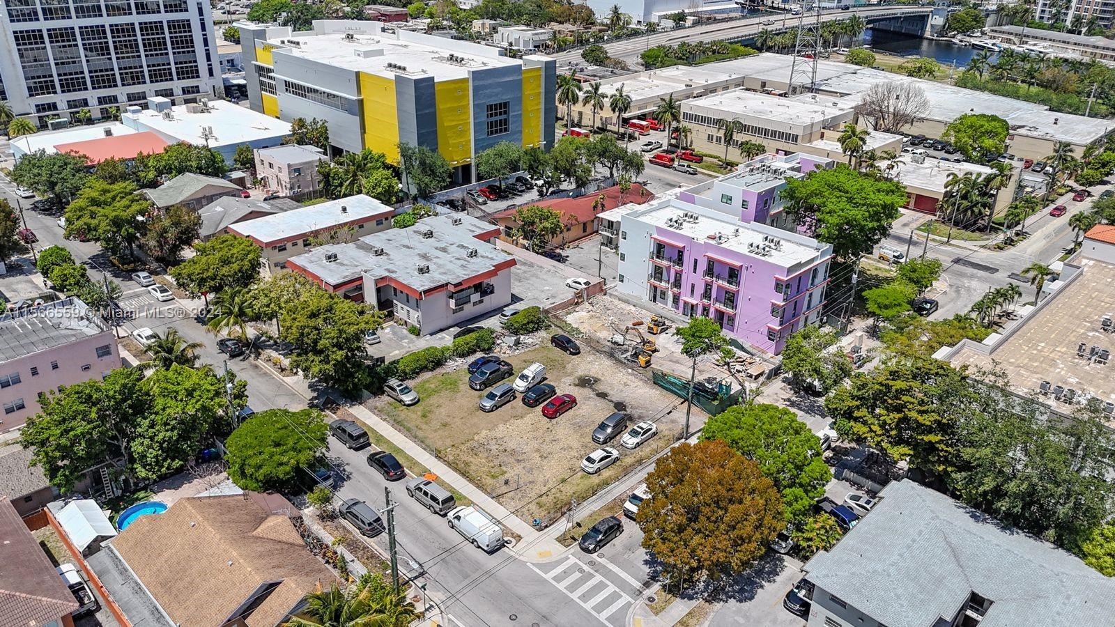 An aerial view shows a vacant dirt lot surrounded by urban buildings and parked cars — 1111 NW 6th St, Miami FL 33136, MIAMI, FL