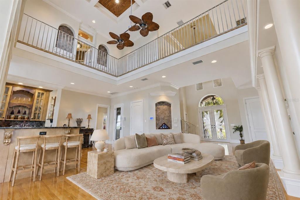 A grand foyer features a curved staircase, a large globe pendant light, and double glass doors — 4631 HARBORPOINTE DRIVE, PORT RICHEY, FL