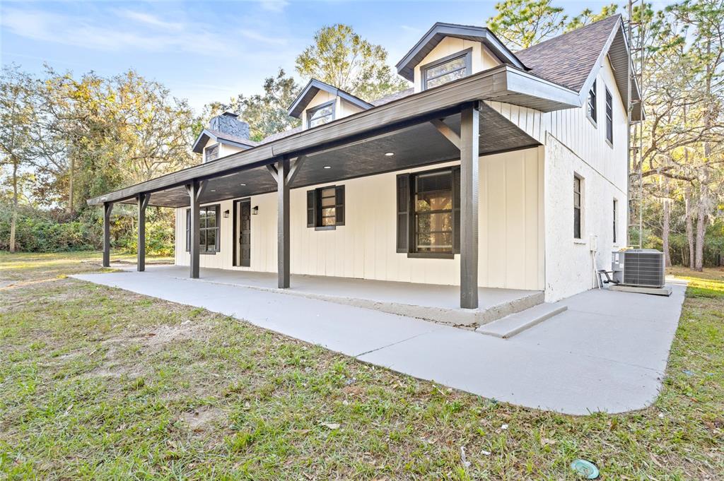 A two-story house with a large covered front porch, board-and-batten siding, and dormer windows — 8057 SHAW ROAD, BROOKSVILLE, FL