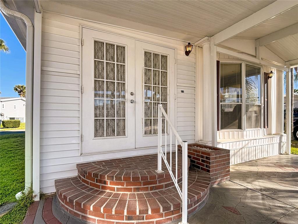 A white house exterior features a brick semi-circular step leading to double glass-paned doors — 9000 US HWY 192 UNIT 849, CLERMONT, FL