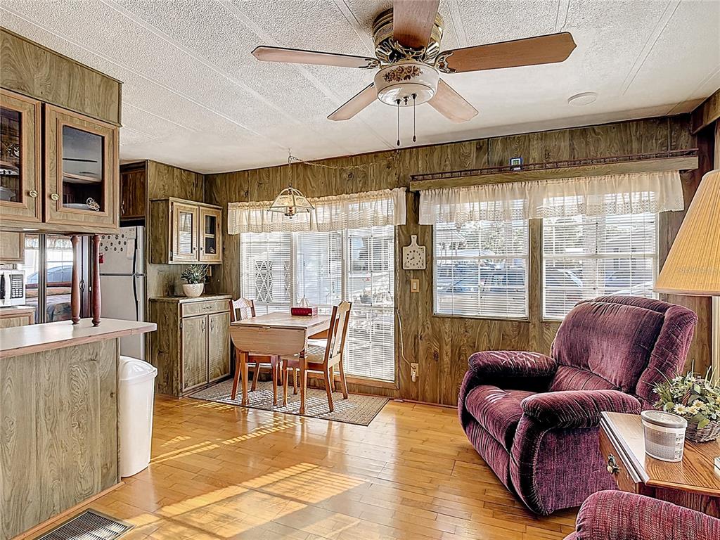 A kitchen and dining area features wood-paneled walls, hardwood flooring, and a ceiling fan — 9000 US HWY 192 UNIT 849, CLERMONT, FL