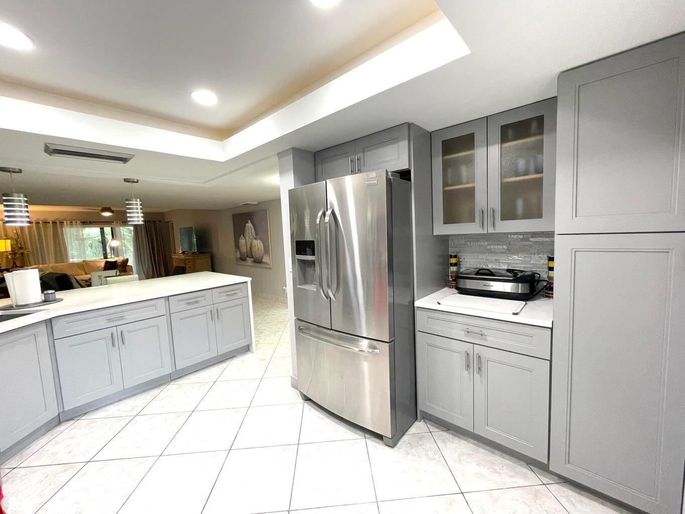 A kitchen features gray cabinets, stainless steel appliances, and white countertops with tile flooring — 1714 Consulate Place # 101, West Palm Beach FL 33401, WEST PALM BEACH, FL